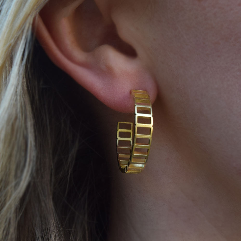 Large minimal gold hoop earrings being worn on the ear