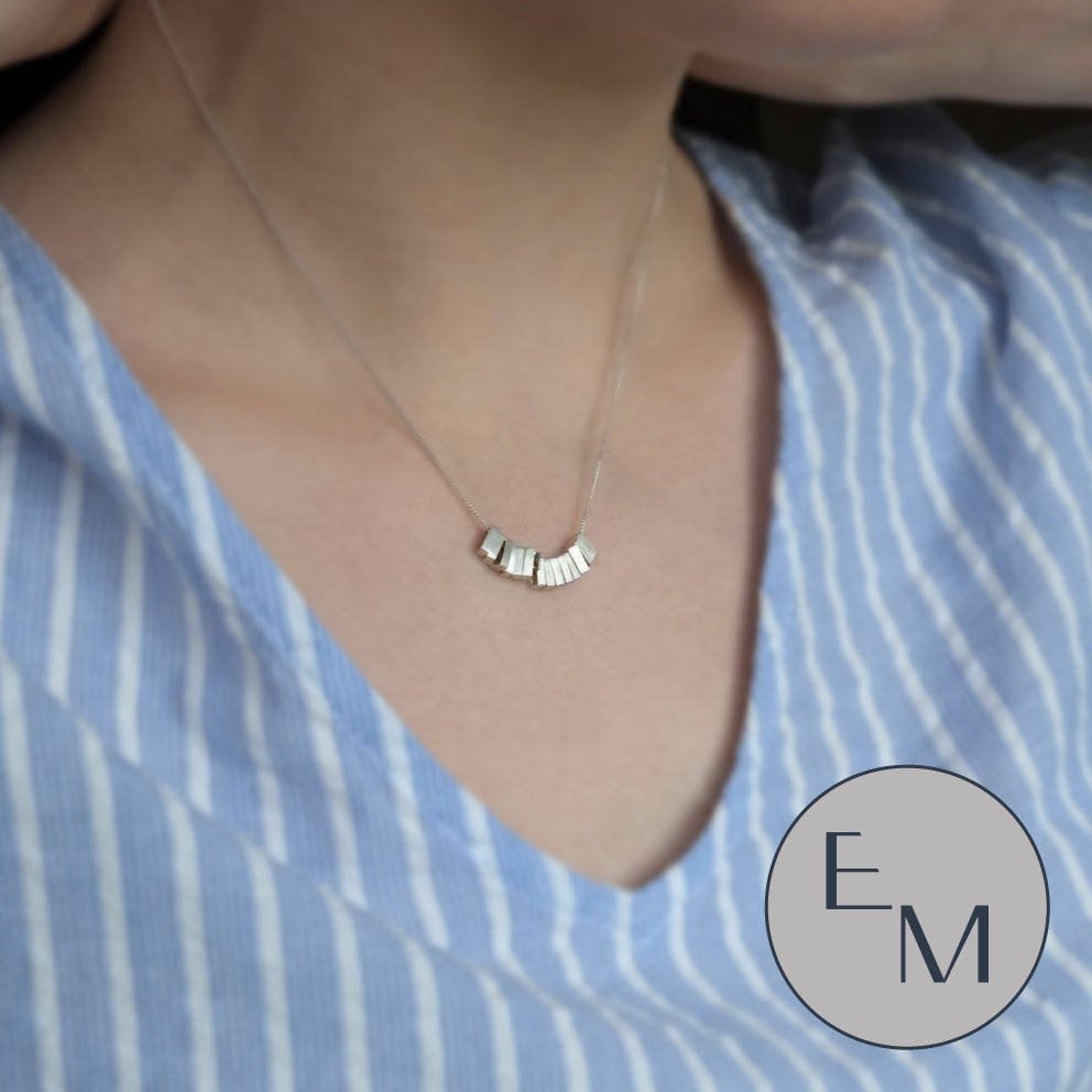 A delicate geometric being worn on a blue shirt