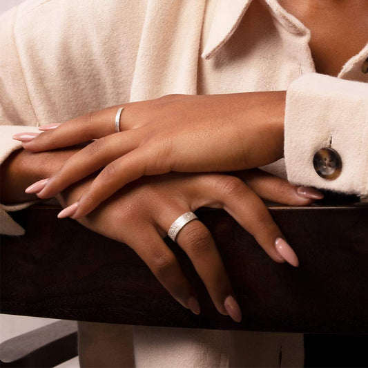 A wide sterling silver textured ring on a hand