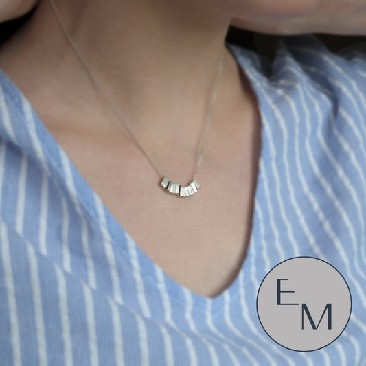A delicate geometric being worn on a blue shirt