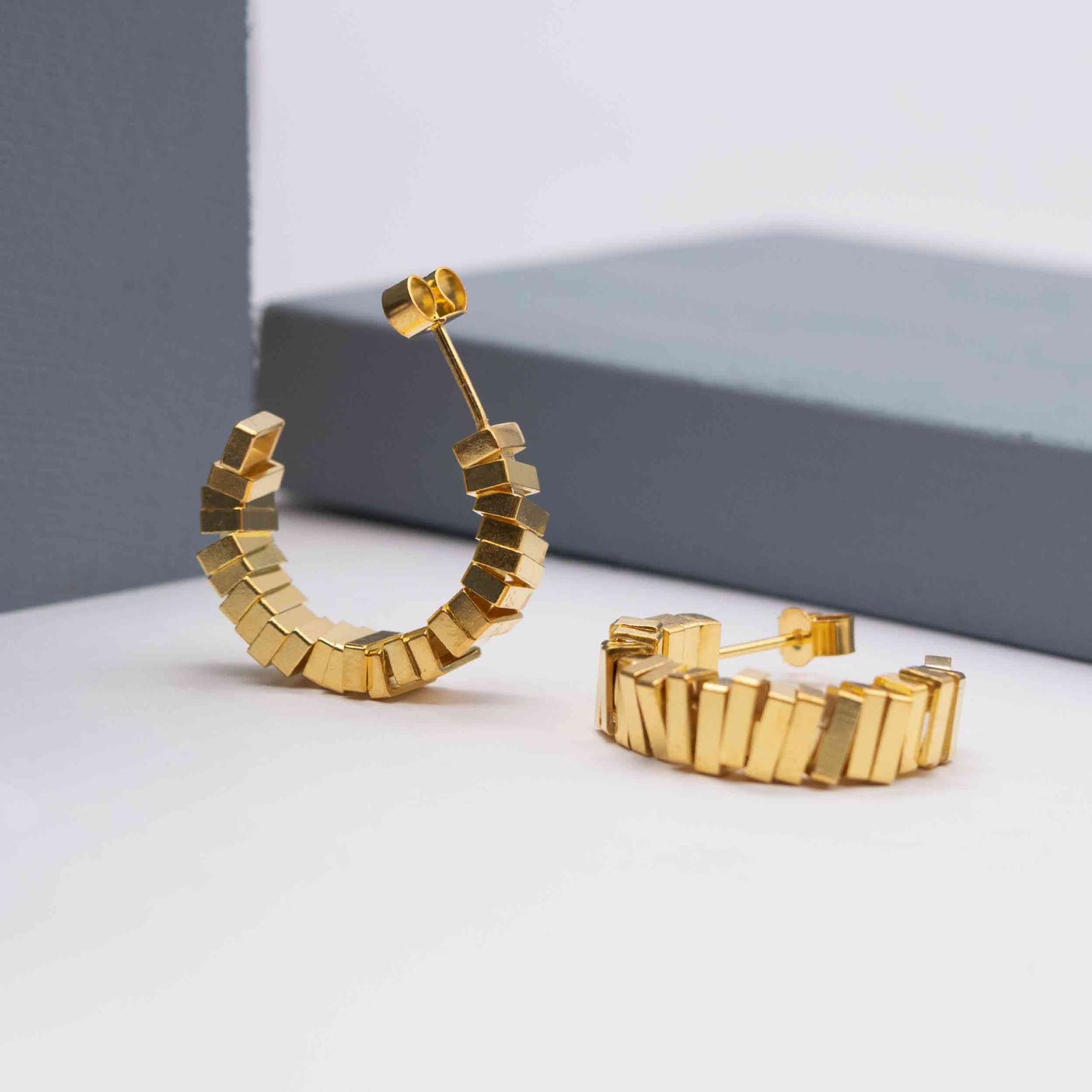 Geometric gold hoop earrings on a white background
