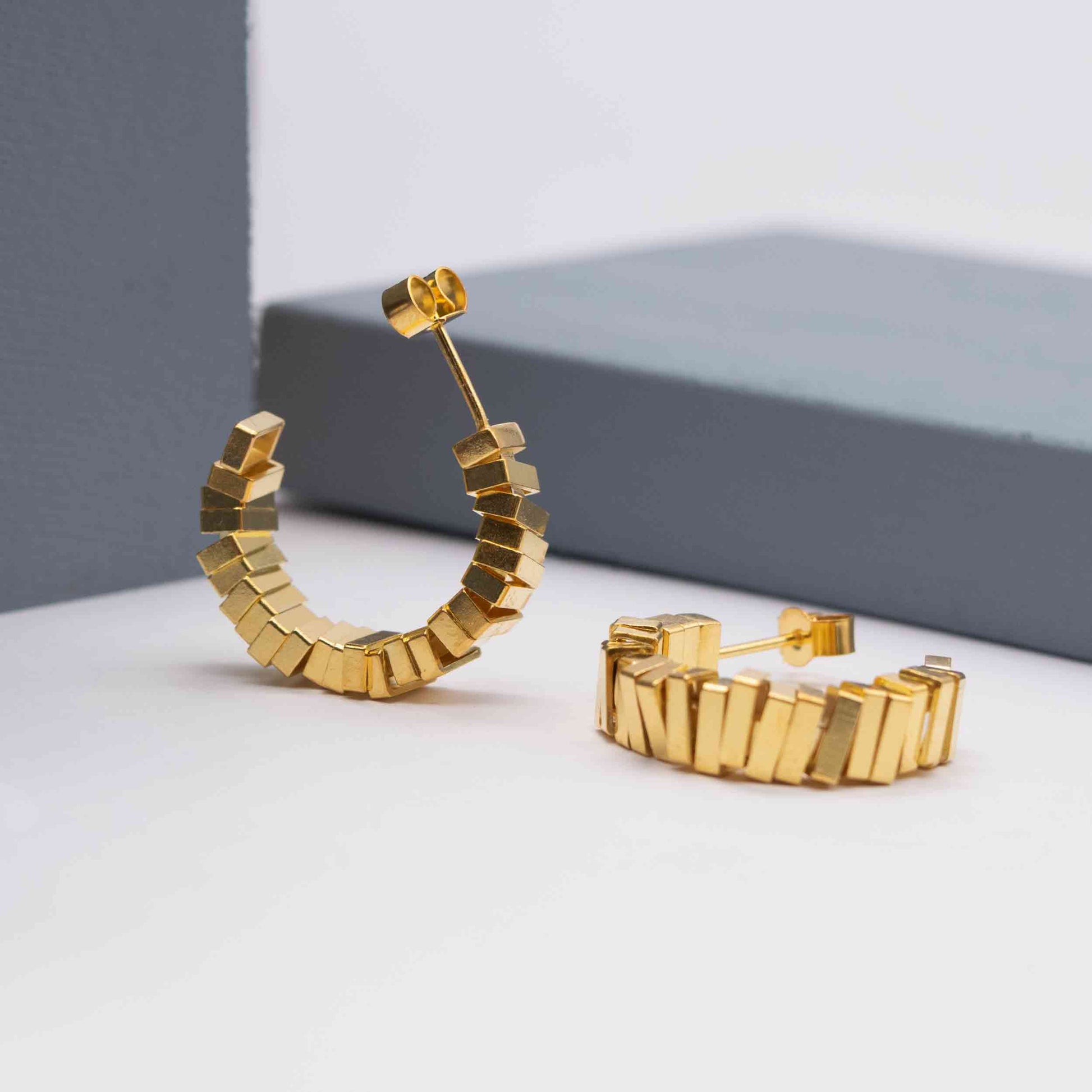 Geometric gold hoop earrings on a white background