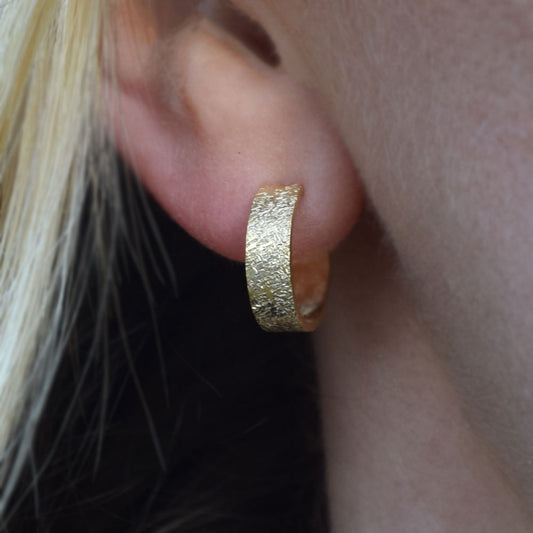 Mini gold hoops being worn on an ear