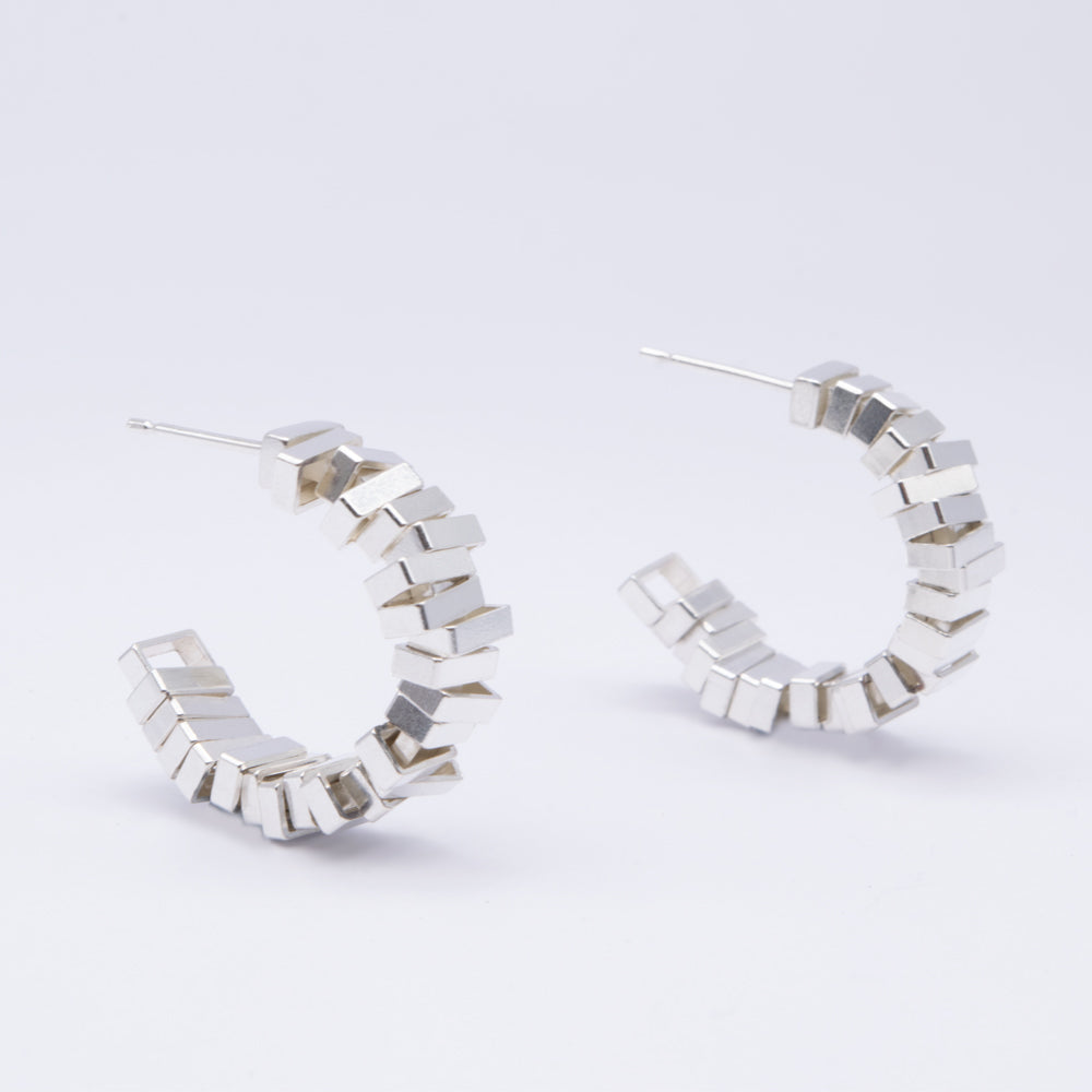 Silver hoop earrings with geometric design on a light gray background