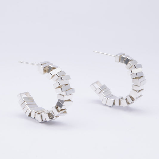 Silver hoop earrings with geometric design on a light gray background