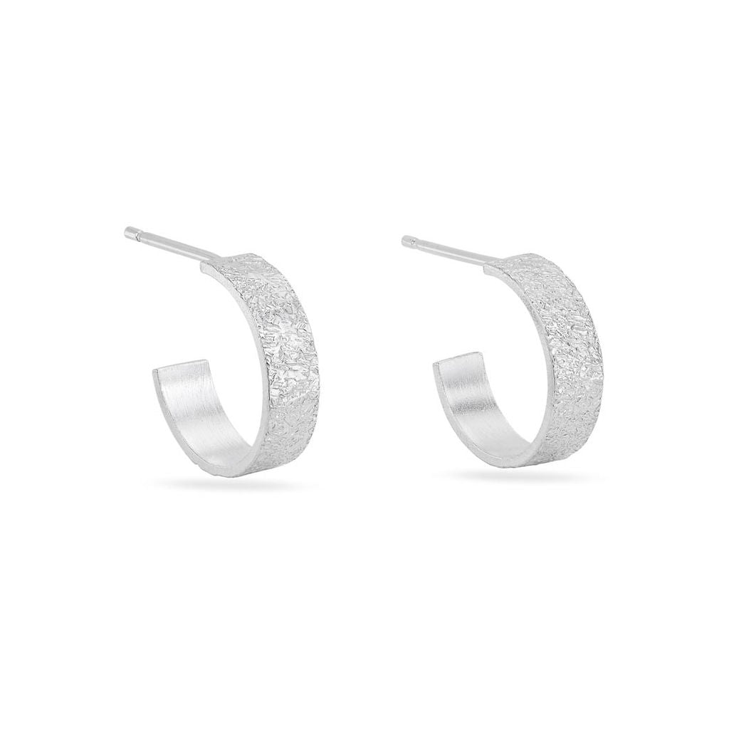 A pair of silver mini textured hoop earrings against a white background.