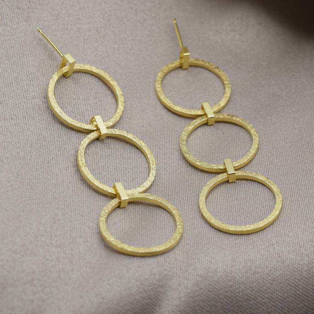 Long textured drop earrings on a fabric background