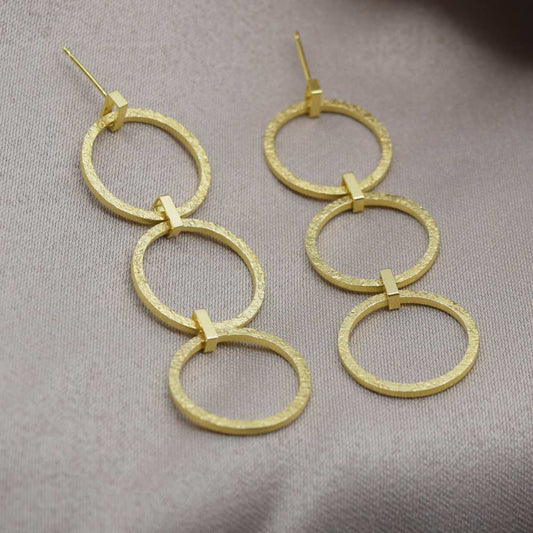 Long textured drop earrings on a fabric background
