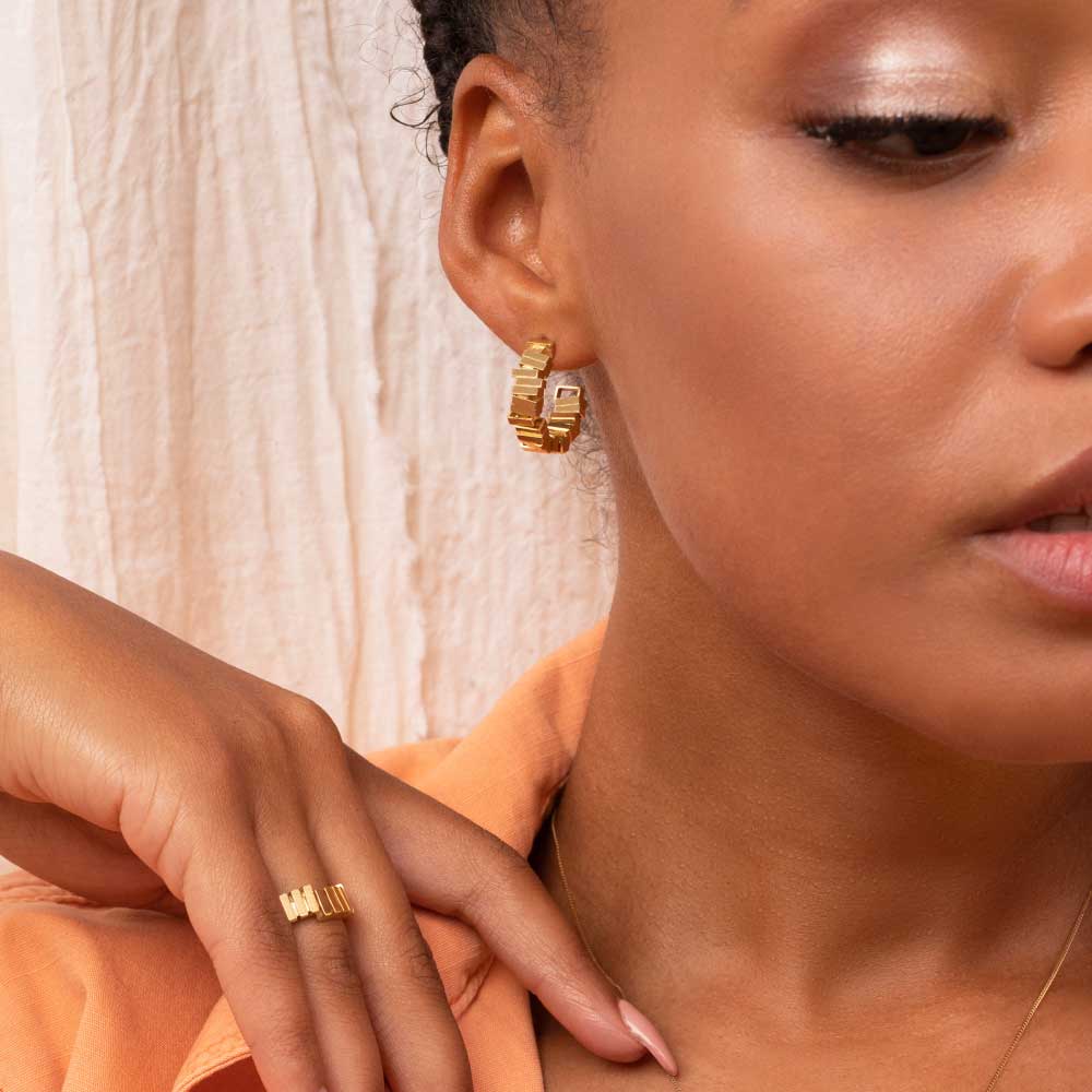 Gold hoop earrings being worn by a model wearing an orange shirt