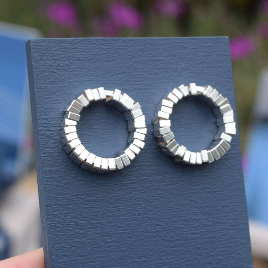 Geometric sterling silver earrings on a blue earring stand