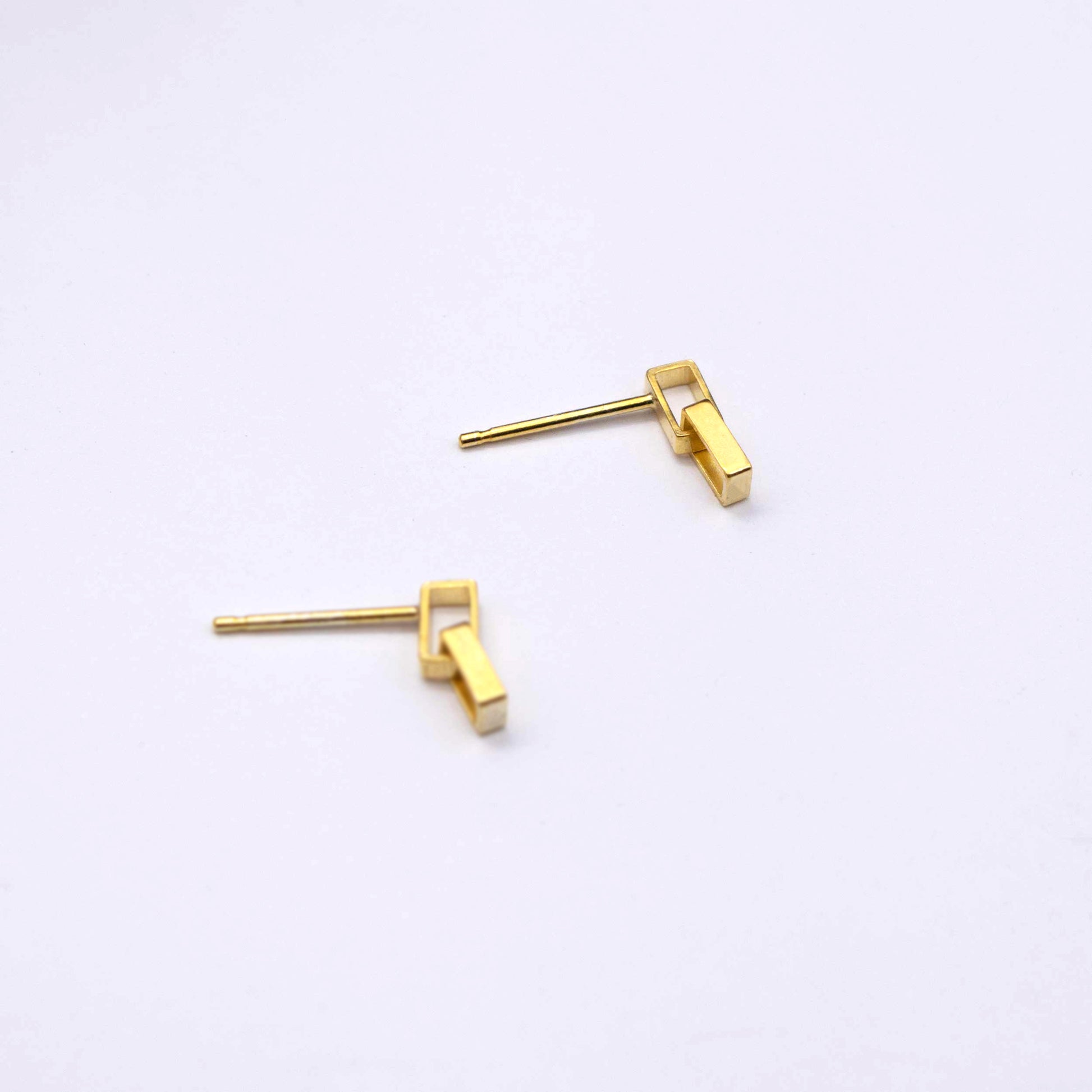 A pair of gold-colored mini brickwork drop stud earrings on a white background.