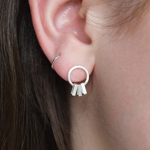 Minimal drop earrings in sterling silver being worn on the ear