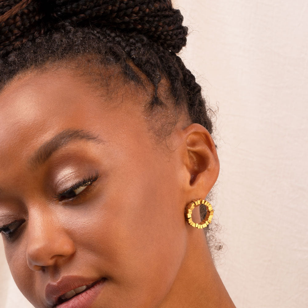 Gold earrings being worn on a model