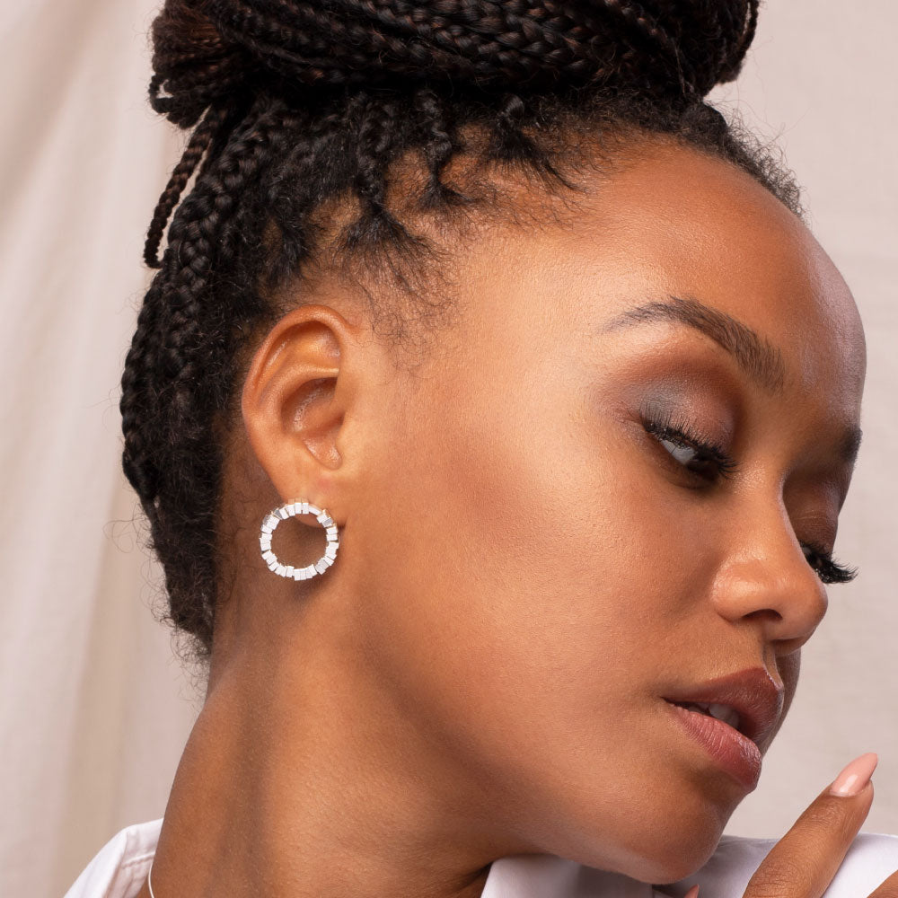 Minimal round earrings being worn on a model with a white shirt
