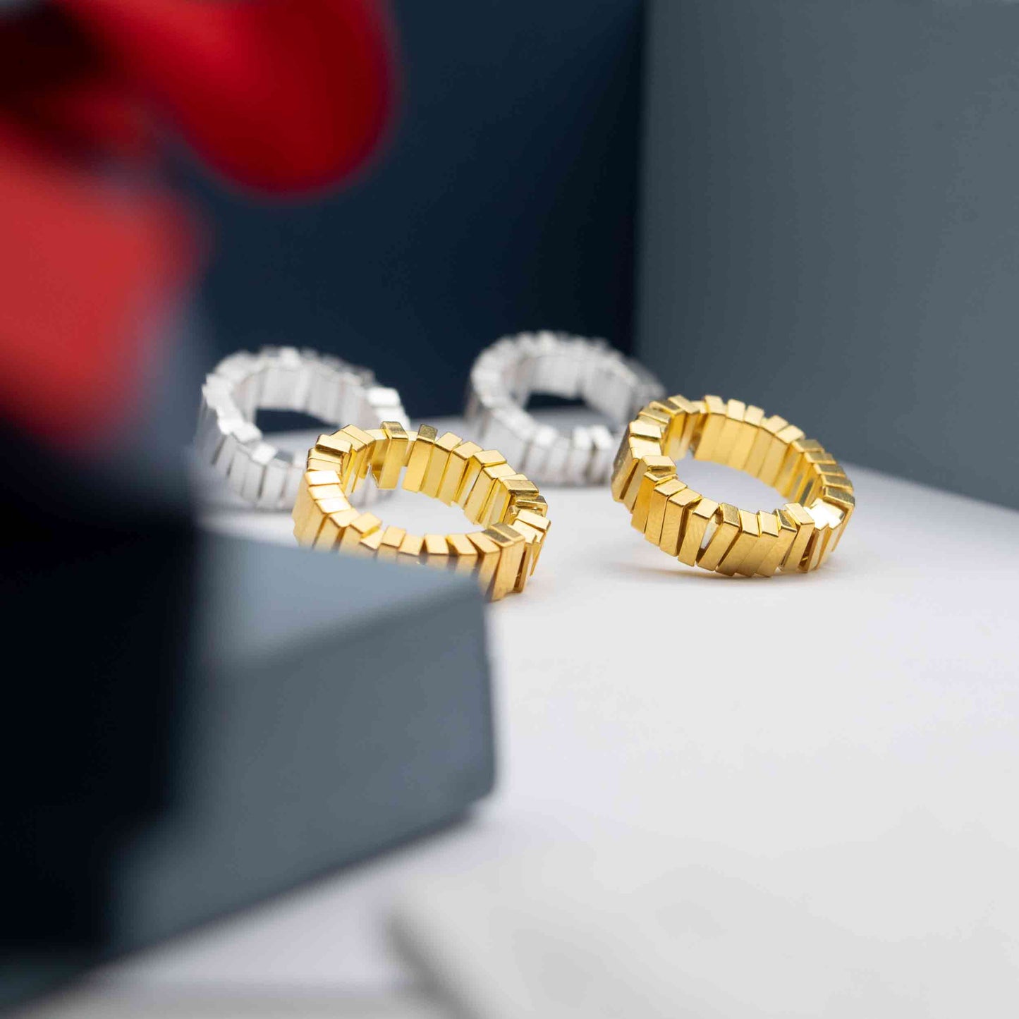 Geometric silver and gold earrings displayed on a blue box